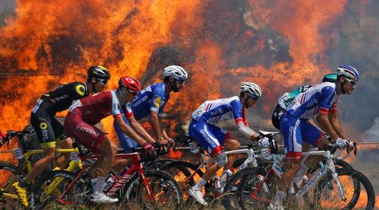 Stunning photo with riders in Tour de France passing by fire!